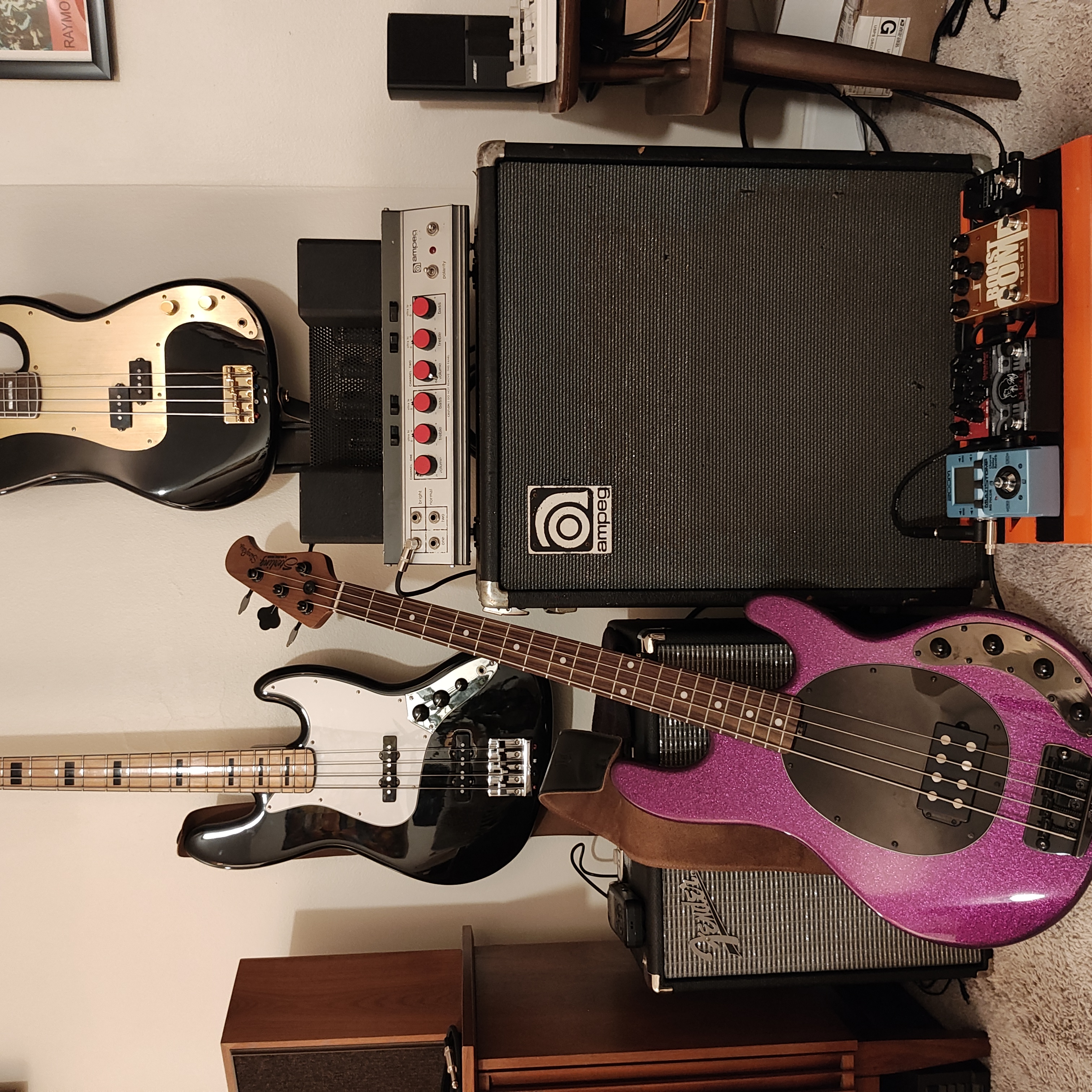 A collection of various bass guitars, amplifiers, and effect pedals